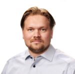 Mies katsoo kameraan ja hymyilee.