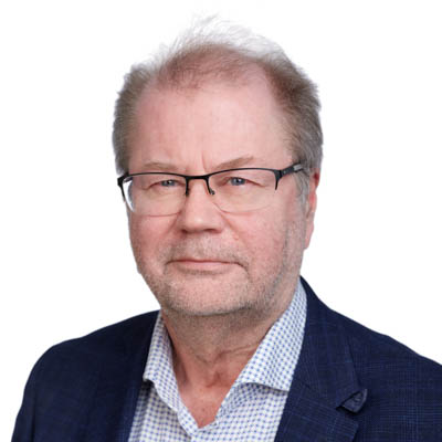 A man wearing glasses looks at the camera and smiles.