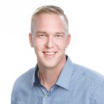Mies katsoo kameraan ja hymyilee.
