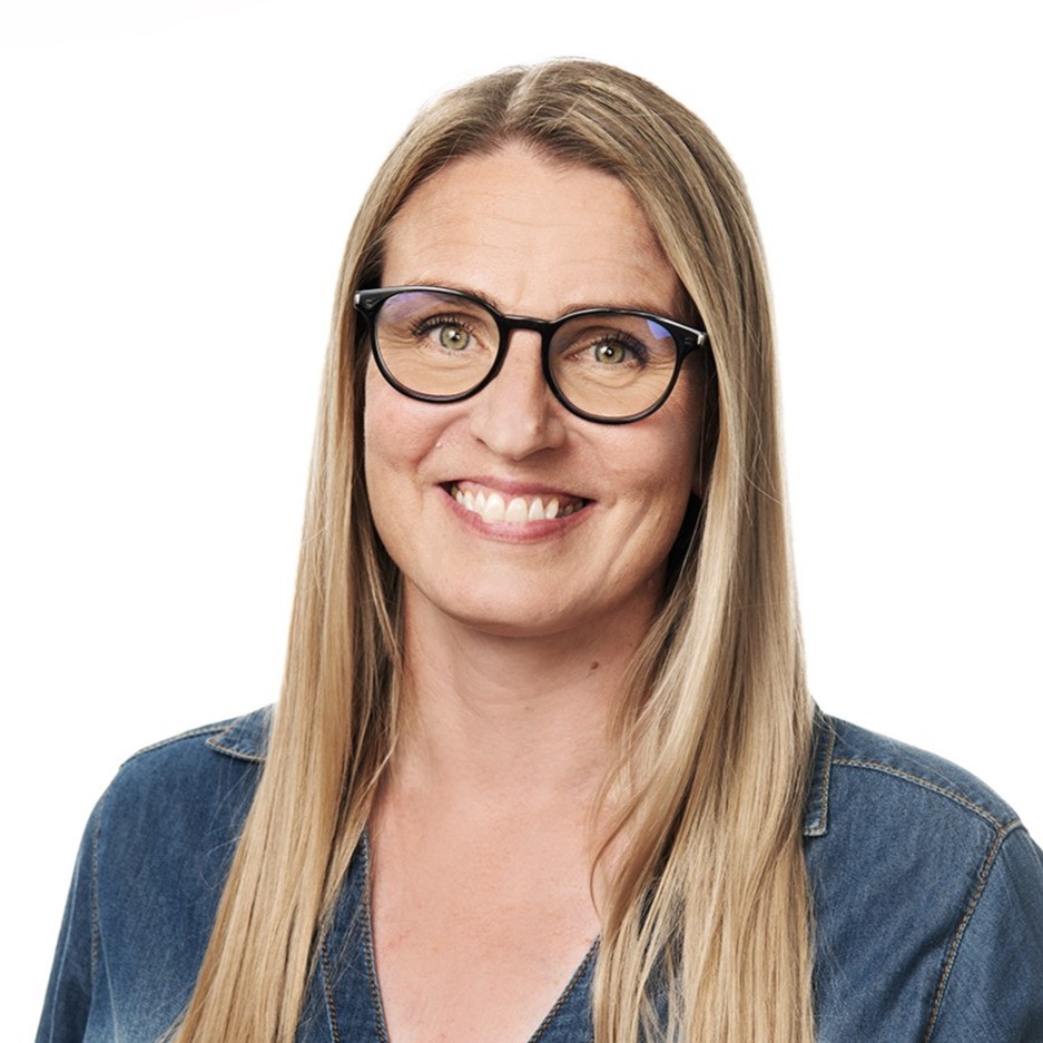 A woman wearing glasses looks at the camera and smiles.
